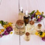 a set of cosmetic, organic and essential oils in various bottles on a white wooden table with meadow medicinal plants. selective focus